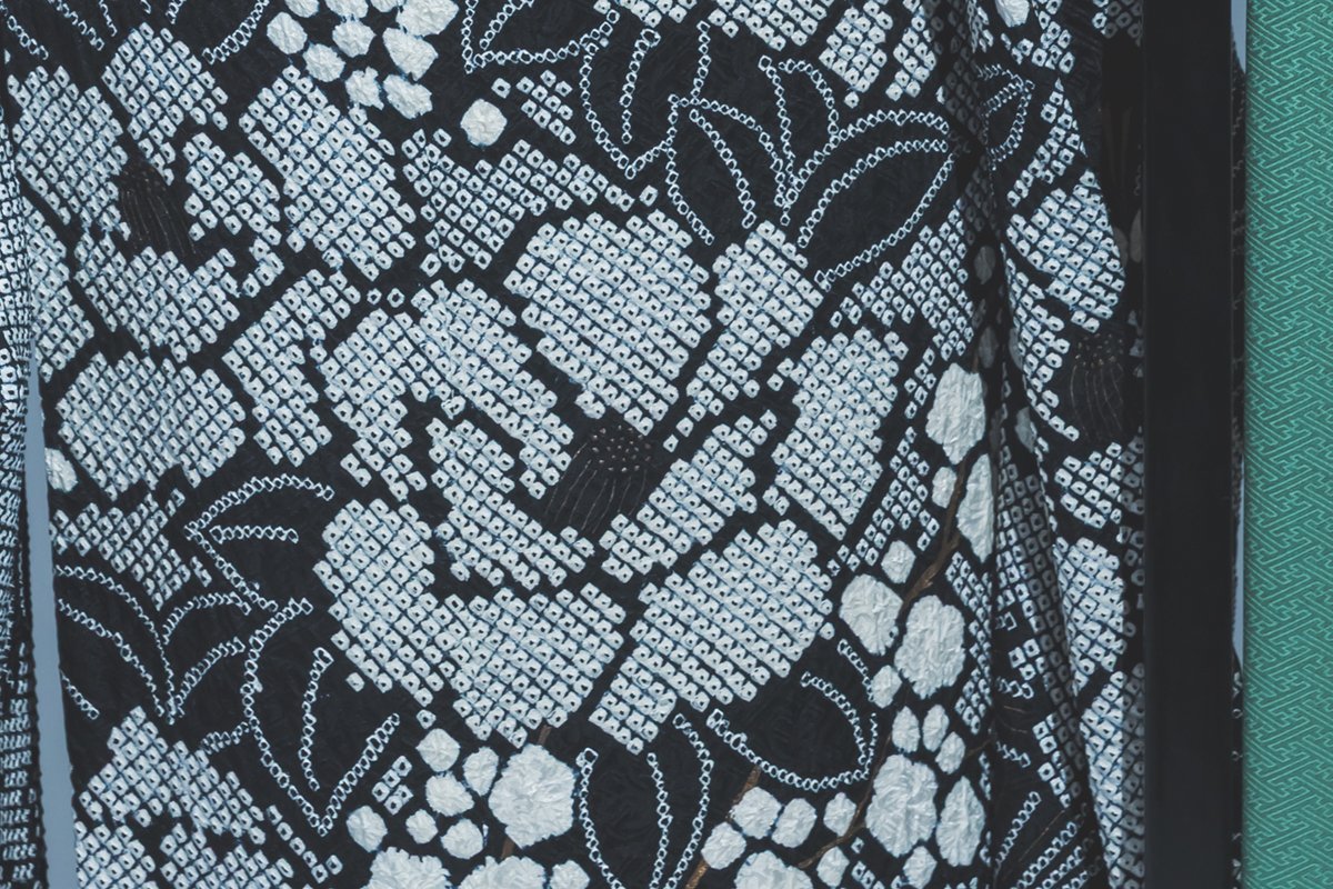 総絞りの生地の寄り。白と黒の小さな粒が並んで花の形を描いている
