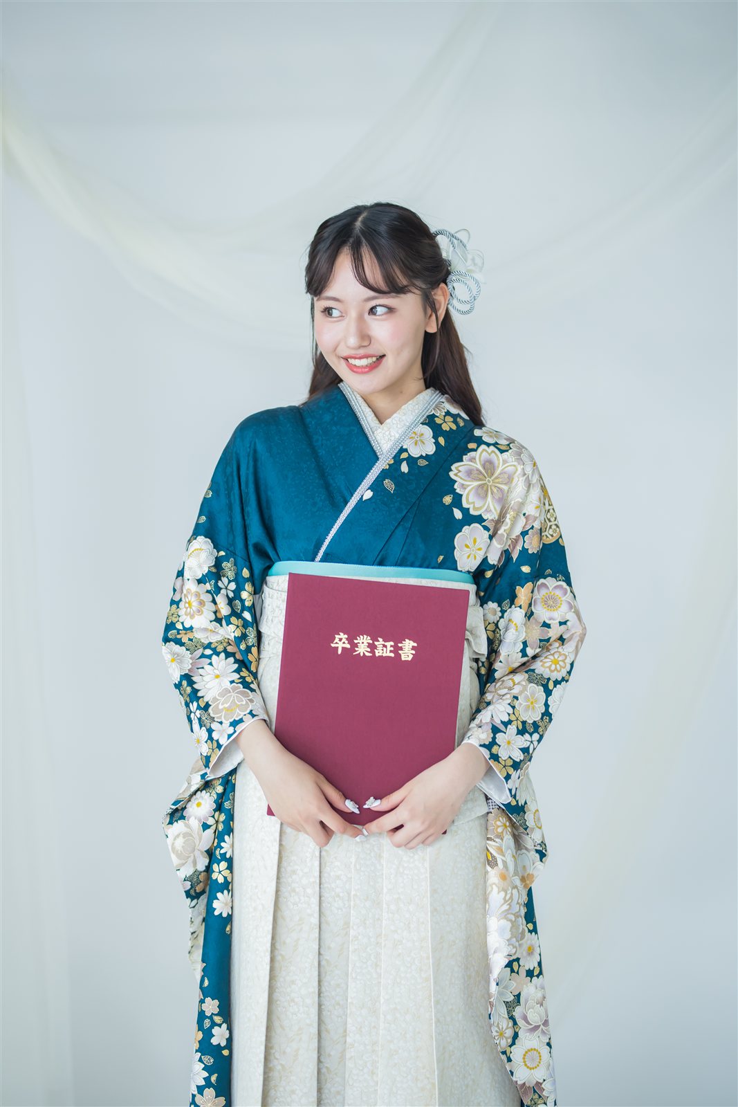 白い袴に青と花柄の二尺袖を合わせ、卒業証書を持った卒業式の装い