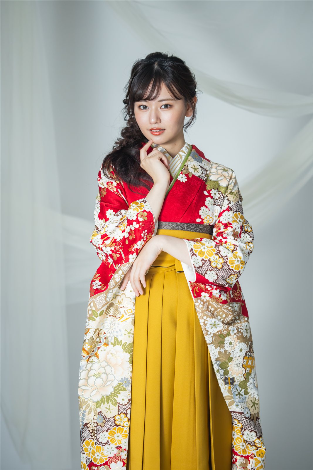 からし色の袴に赤い花柄の着物を合わせ、ブーツをはいた卒業式の装い