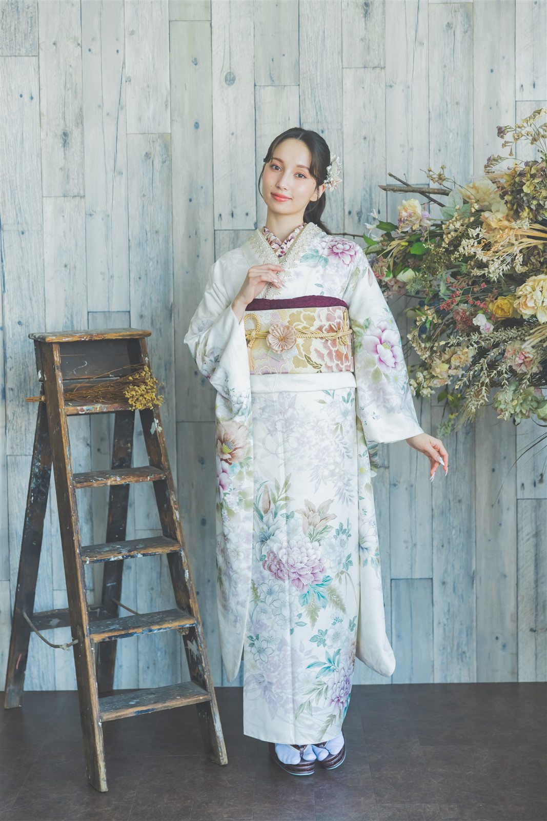 白地に花の振袖の全身。木のはしごと花を飾ったスタジオの背景