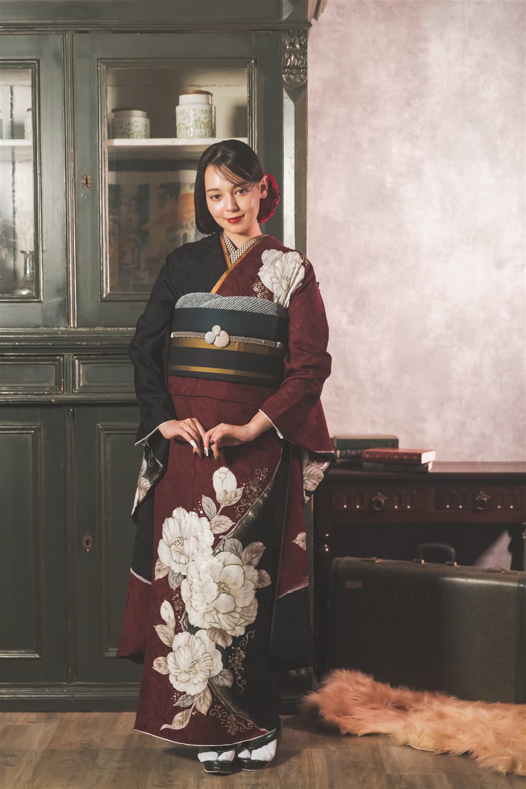 左右で深紅と黒に分かれた大正ロマン振袖に、縞の帯と深紅の髪飾りを合わせた全身