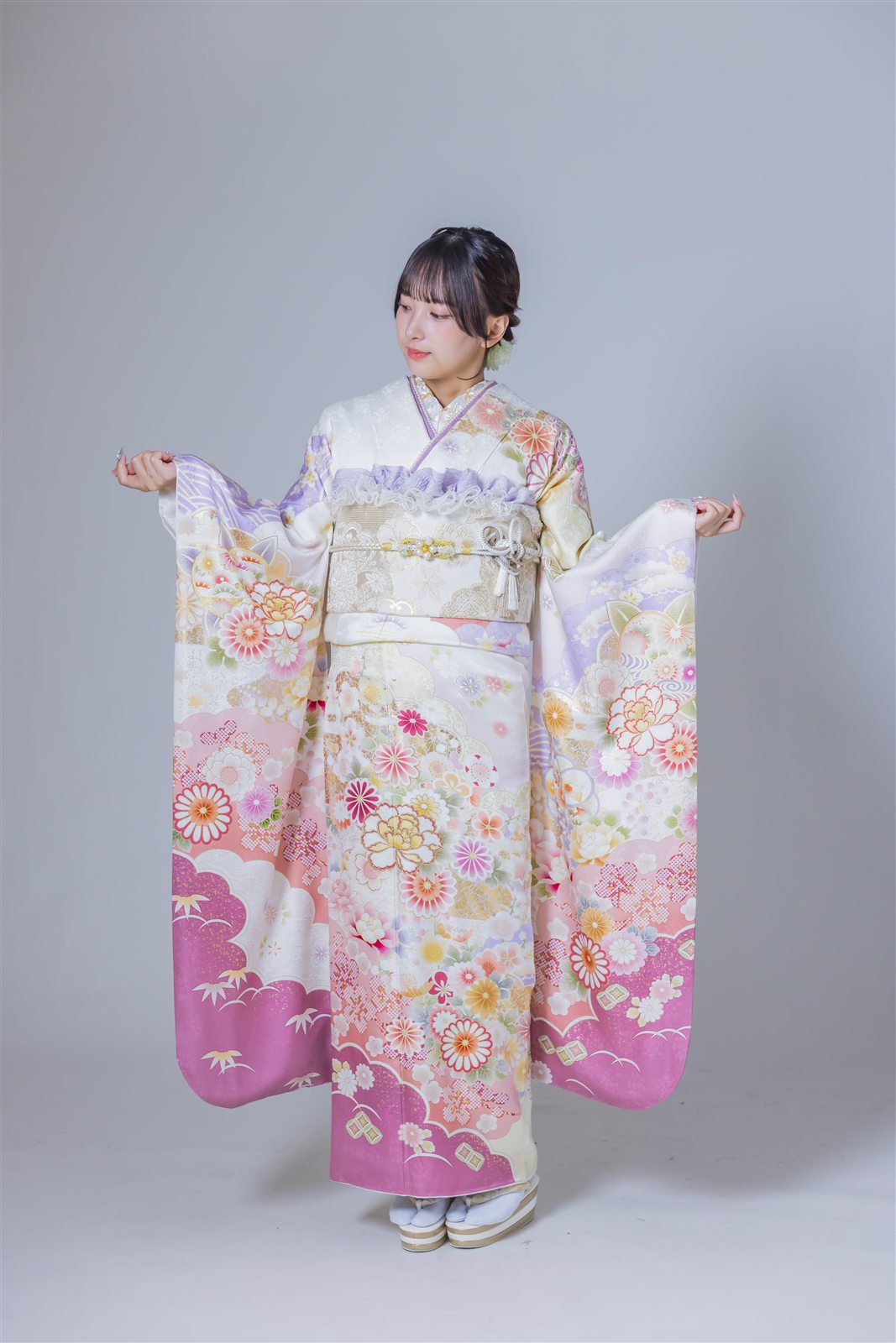 白地に淡いピンクの裾ぼかしと花の柄が入った振袖の全身